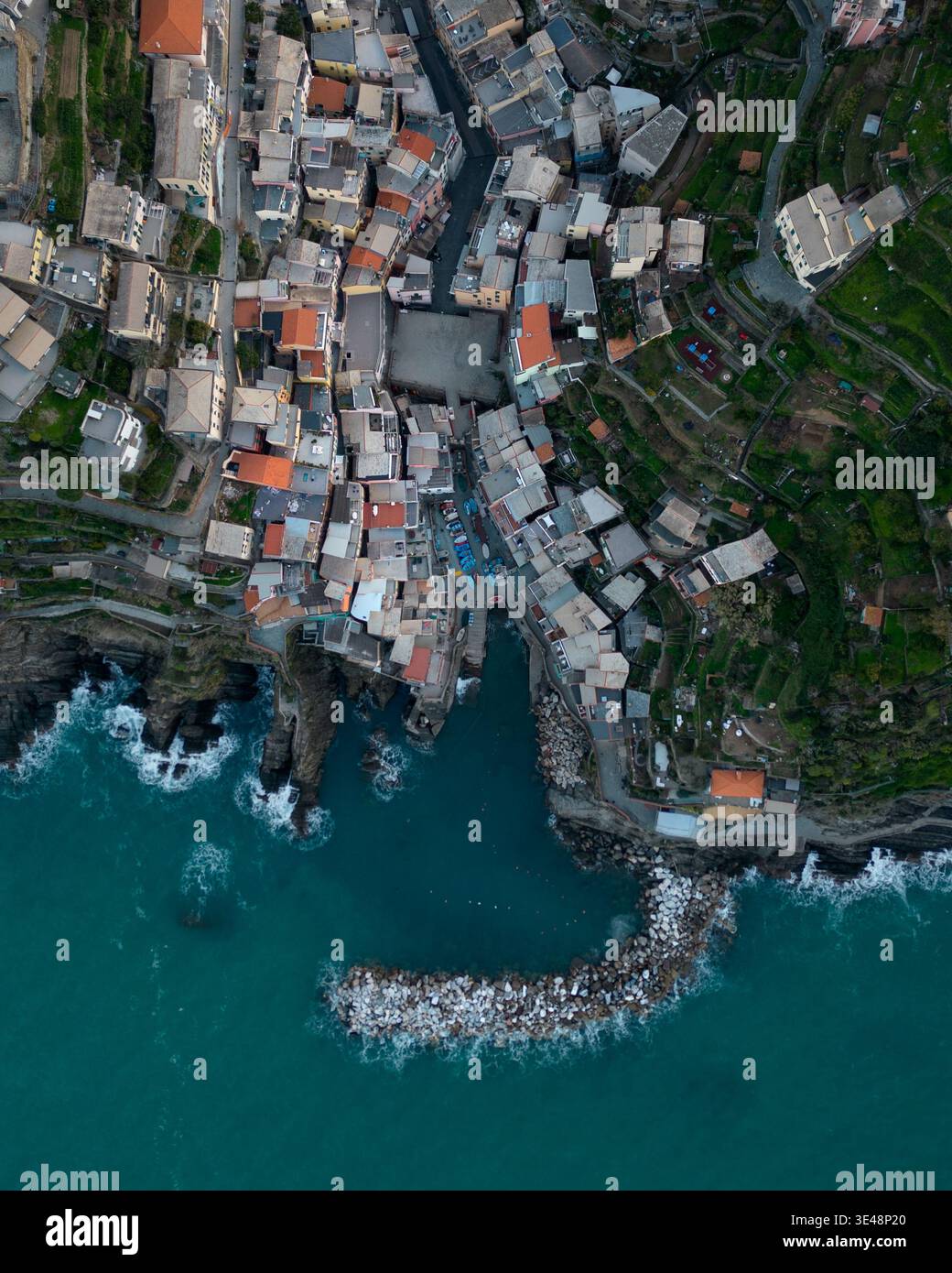Aus der Vogelperspektive auf die farbenfrohen Häuser und den kleinen Hafen mit einem Steinbruch in Riomaggiore, Ligurien, Italien. Stockfoto