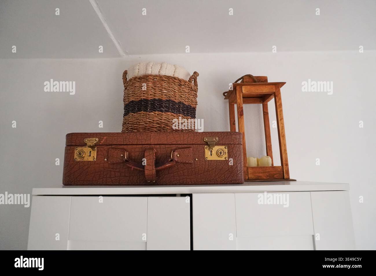 Dekorative Regale mit Vintage-Koffer, gewebtem Korb und Laterne für gemütliche häusliche Ästhetik Stockfoto