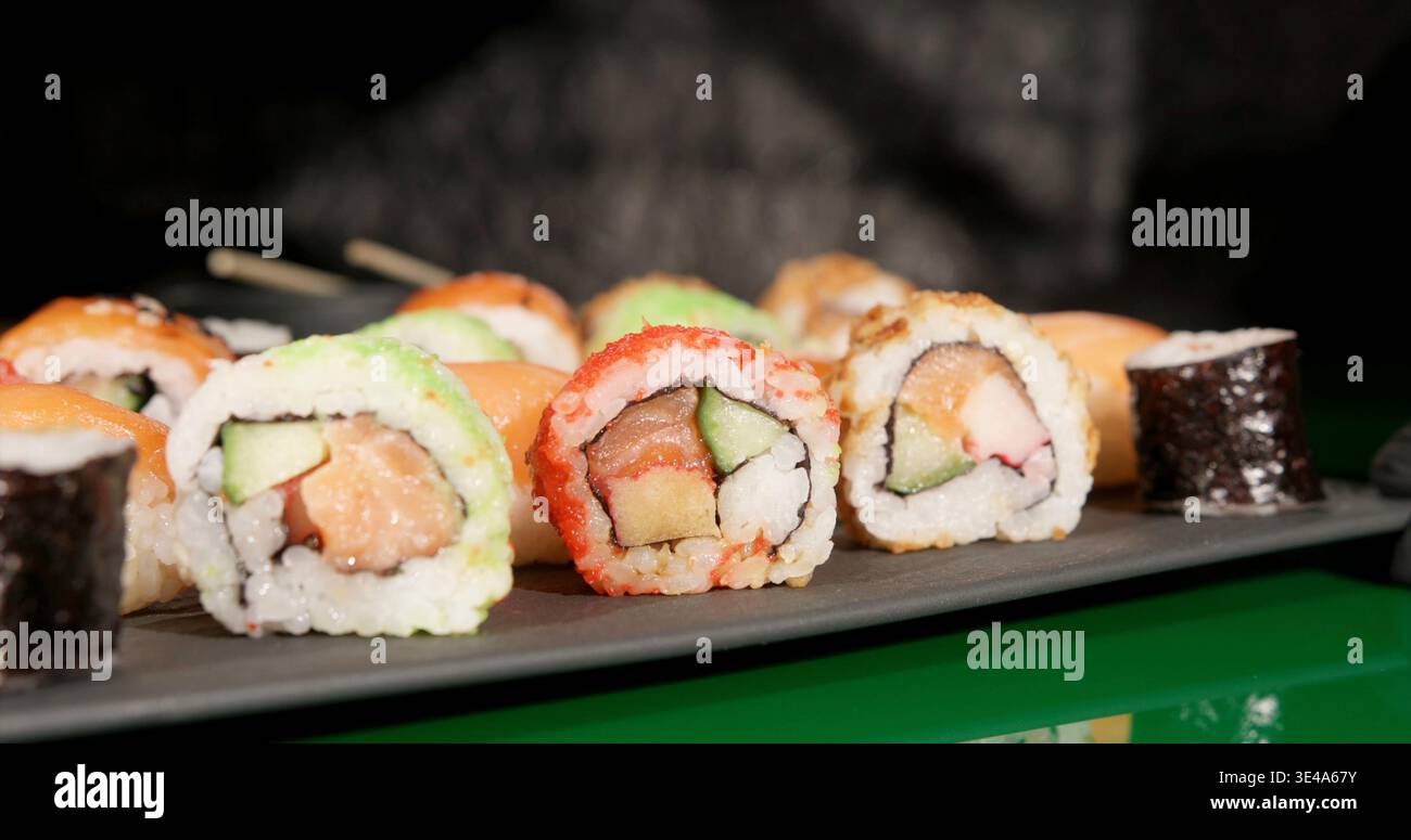 Sushi-Brötchen werden während des Abendessens in einem Restaurant auf einem schwarzen Teller serviert Stockfoto