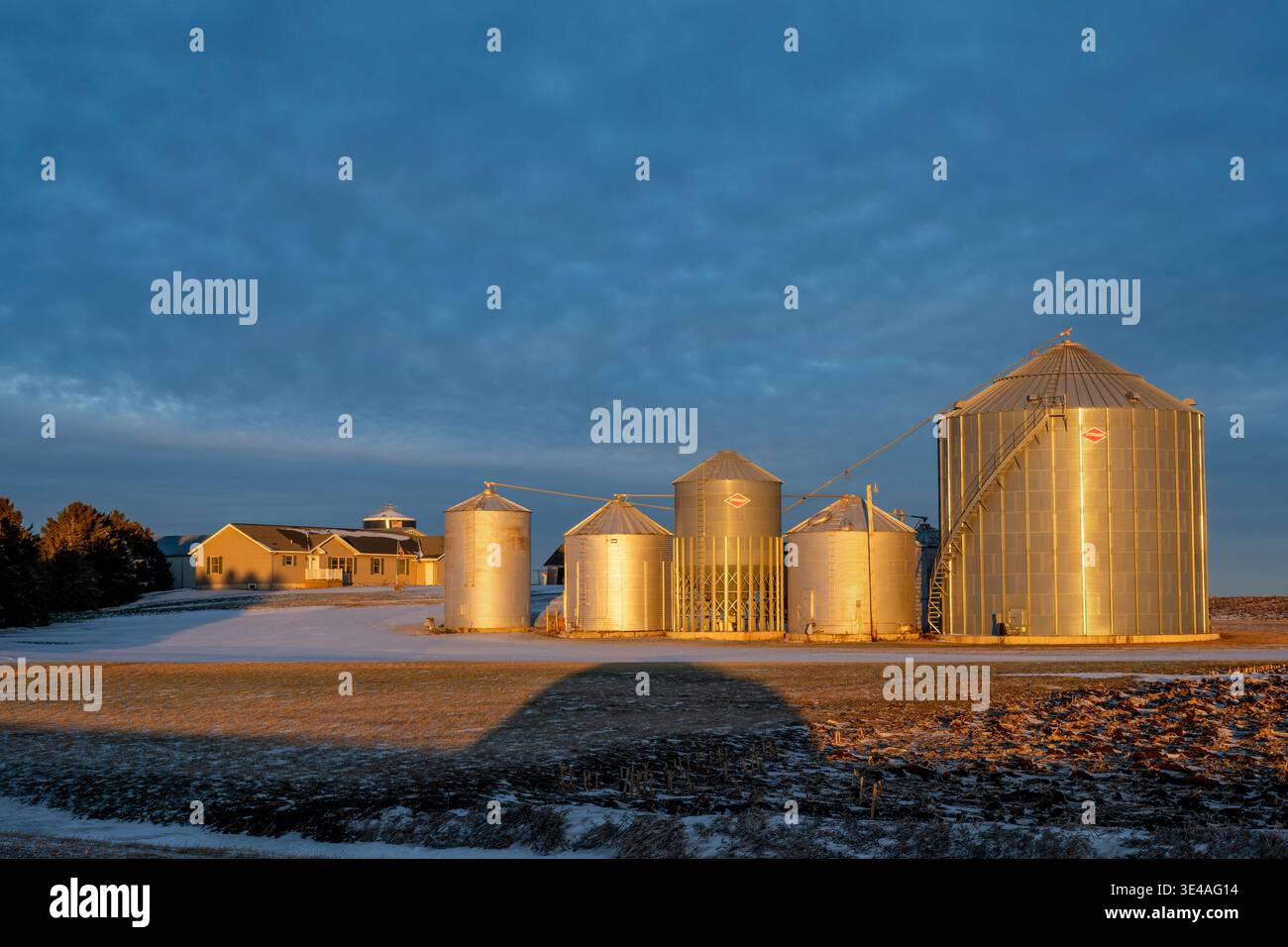 Williams, Iowa. Gut gepflegter Bauernhof mit Getreidebehältern zur „goldenen Stunde“ Sonnenuntergang im Winter. Stockfoto