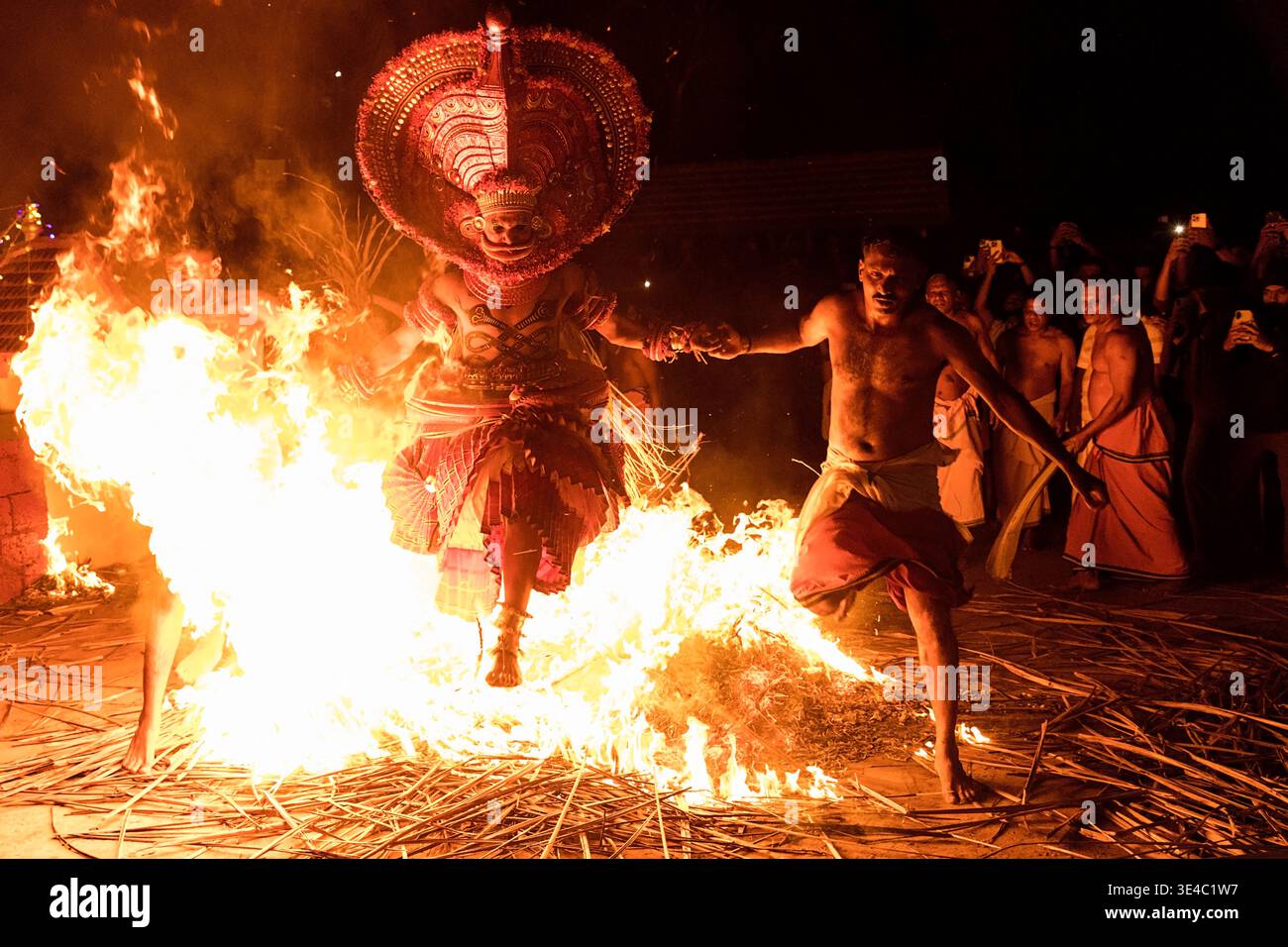 Theyyam-Darsteller hüpfte während eines traditionellen Nachtrituals in einem Dorf in der Nähe von Kannur, Kerala, Indien durch das Feuer Stockfoto
