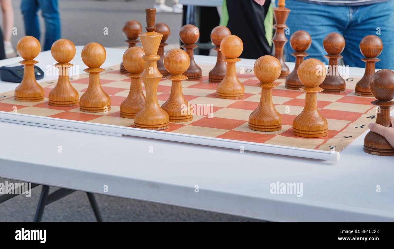 Nahaufnahme eines hölzernen Schachspiels auf einem karierten Brett während eines Spiels im Freien. Stockfoto