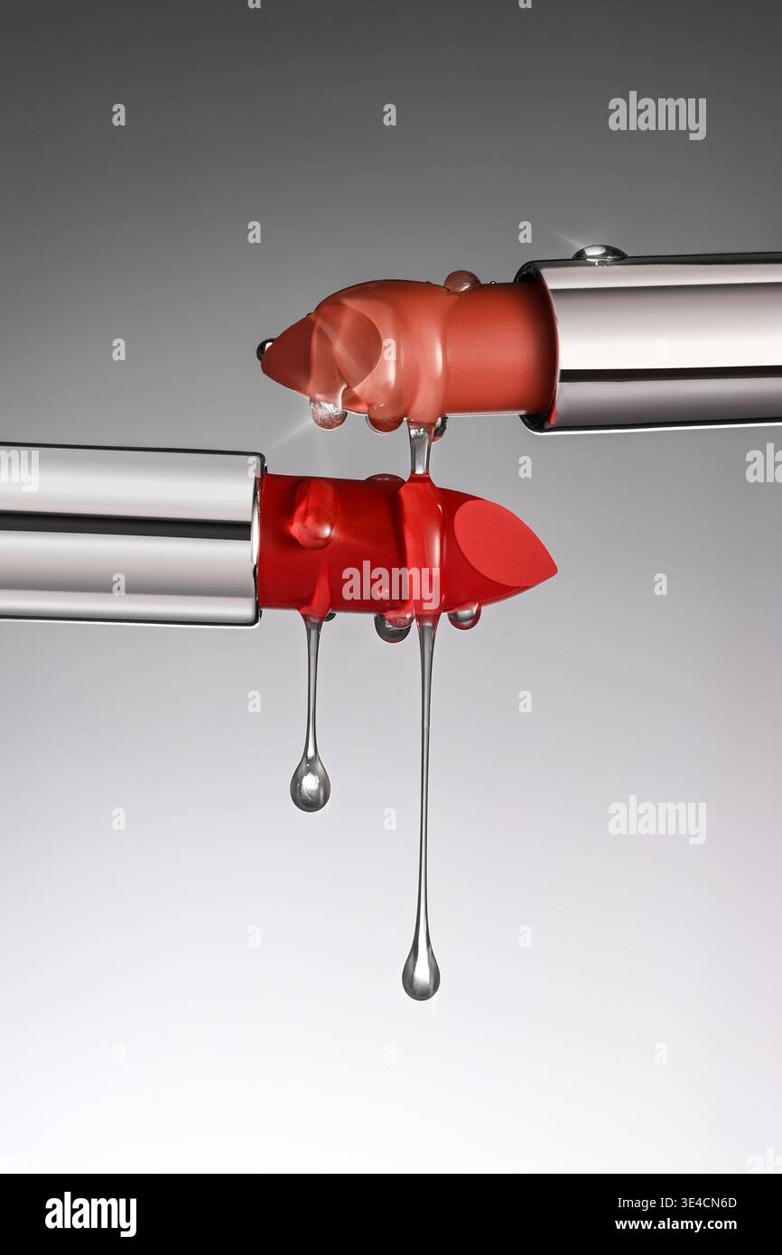 Gebrochener Lippenstift mit tropfenden Flüssigkeitstropfen auf grauem Hintergrund. Stockfoto