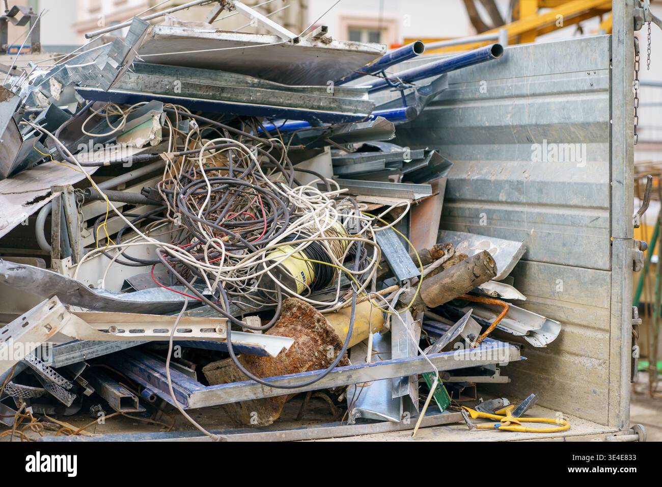 Haufen von Schrott, Kabeln und Bauschutt in einem Behälter, wobei Recycling, Abbruchabfälle und Entsorgungsverfahren für Industriematerialien hervorgehoben werden Stockfoto