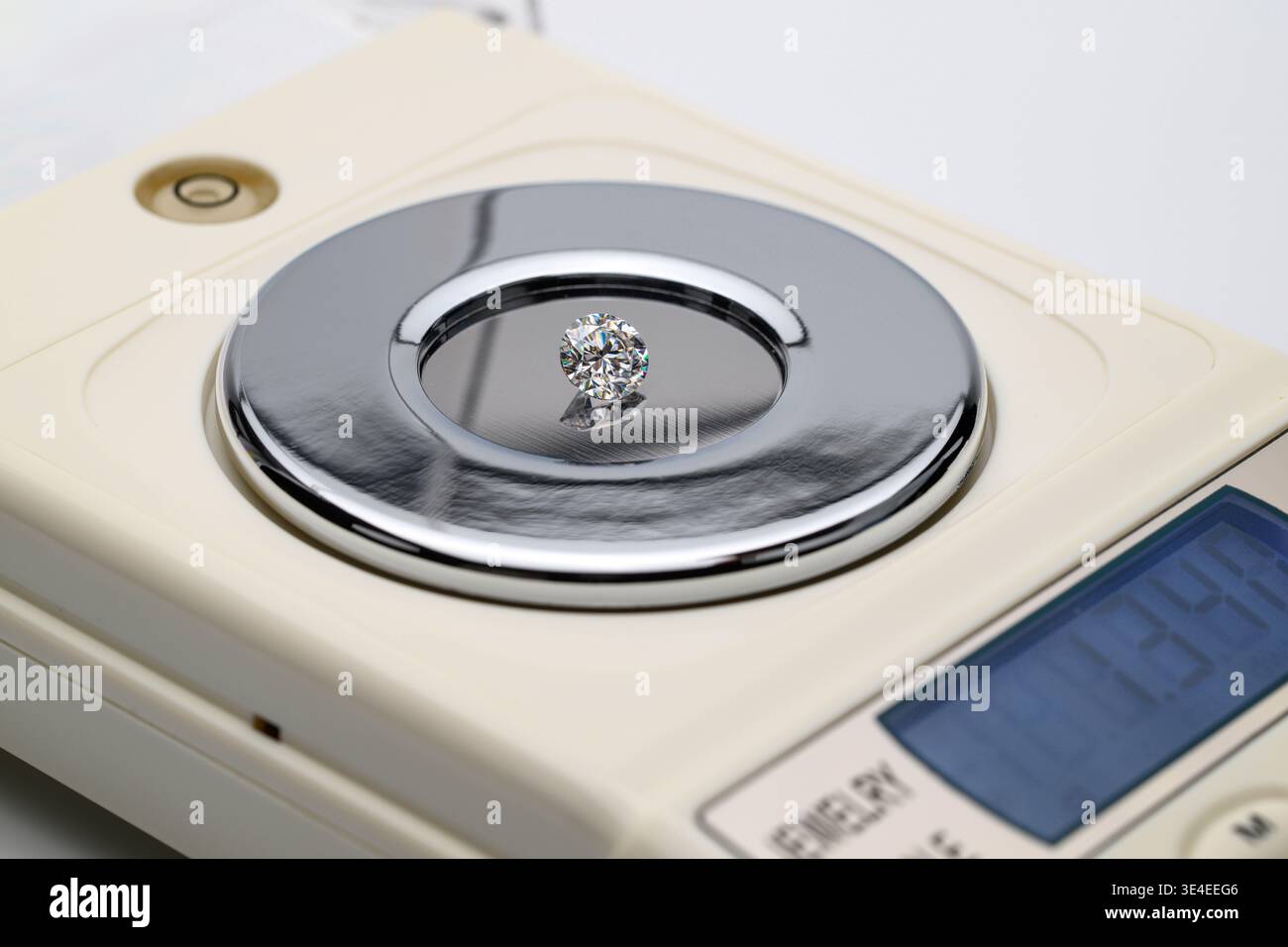 Kleiner, funkelnder Diamant liegt auf einer digitalen Skala auf Stockfoto