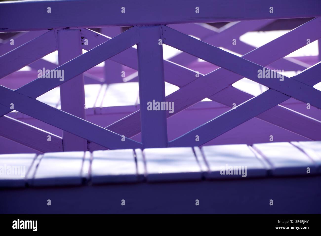 Wunderschöne Sonnenstrahlen tanzen auf einem violetten Holzgerüst und schaffen einzigartige Muster. Stockfoto