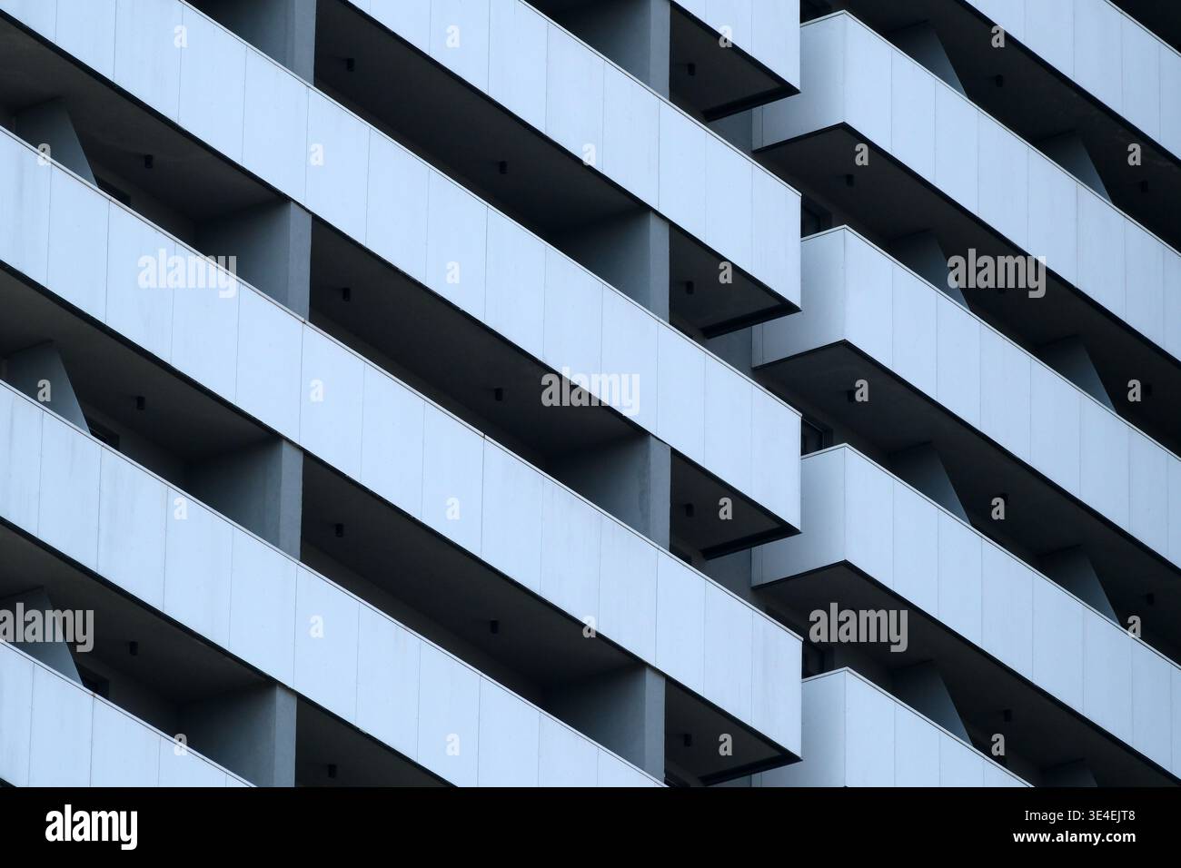 Die hohe Gebäudefassade ist mit einem Muster aus Balkonen und minimalistischem Design gestaltet. Stockfoto