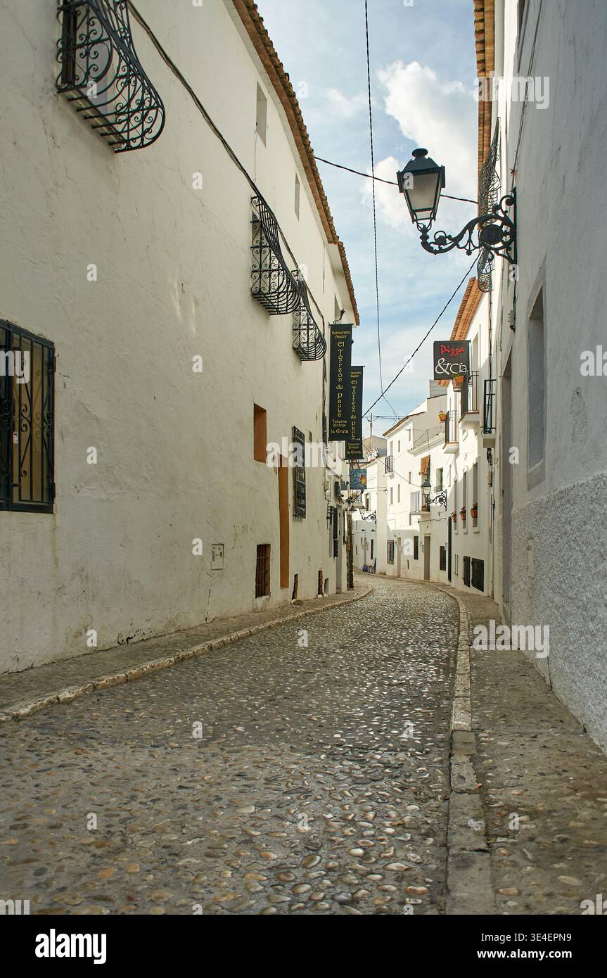 Enge Kopfsteinpflasterstraße mit traditionellen weiß getünchten Gebäuden und schmiedeeisernen Balkonen in der Altstadt von Altea, Alicante, Costa Blanca, Spanien, Stockfoto