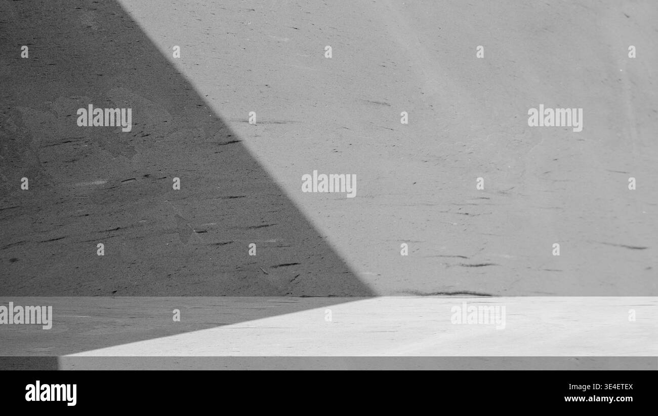 Moderner grauer Zementboden mit natürlichem Licht und Schatten. Dunkelgraue Betonwand mit ästhetischem diagonalem Schatten. Leeres Zementpodium für Luxusprodukt d Stockfoto