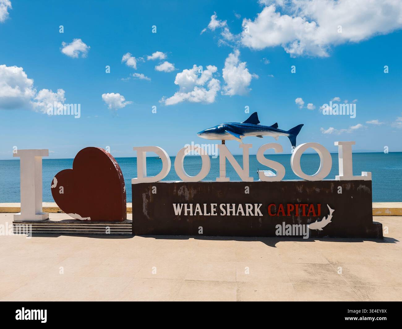 Schild „I ❤️ Donsol“ in Donsol mit einem Walhai. Donsol ist bekannt als die Hauptstadt der Walhaie auf den Philippinen. Meerblick und klarer blauer Himmel - Smartphone-aufgenommenes Stockfoto