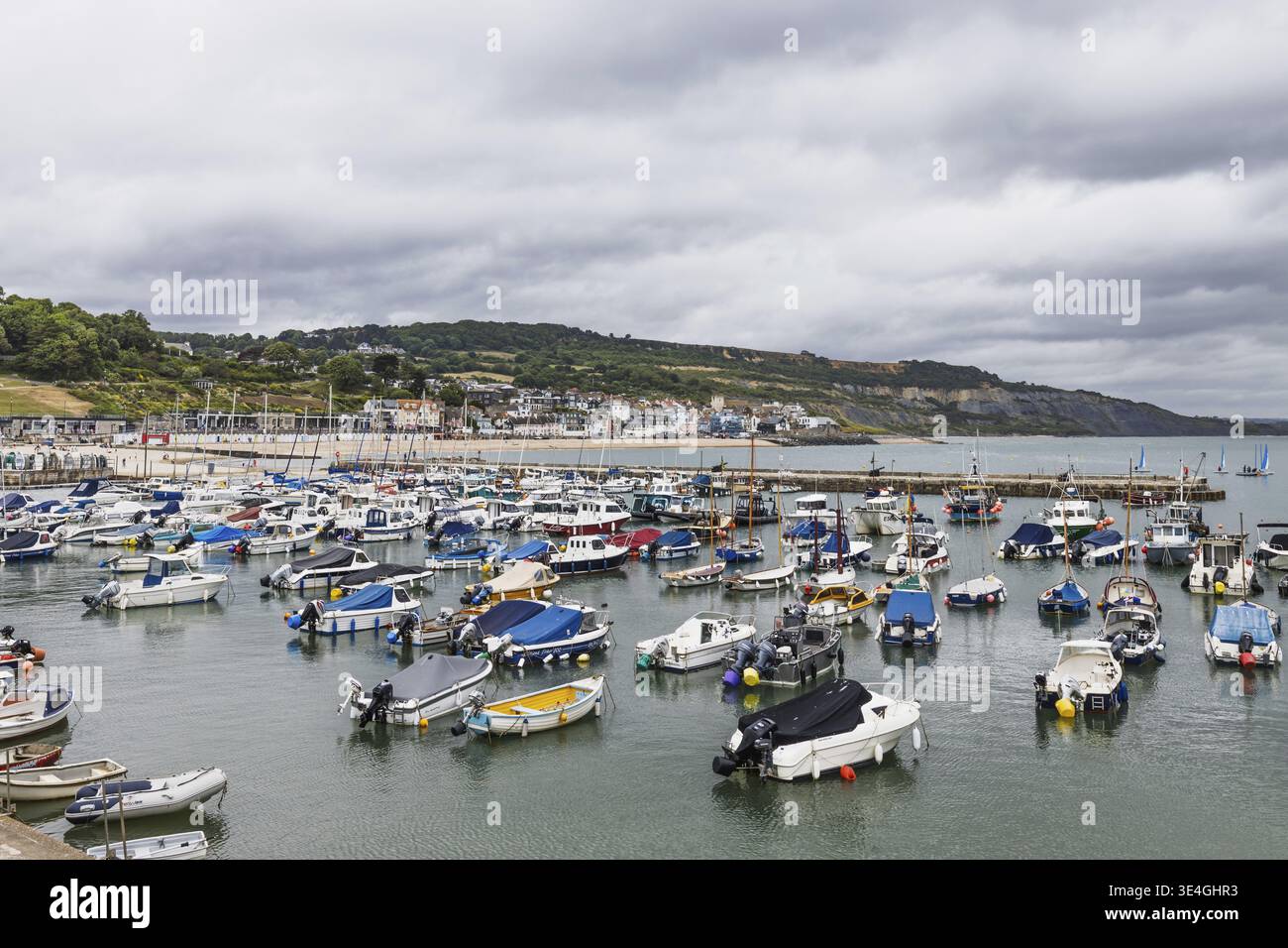 Der Hafen von Lyme Regis mit kleinen Booten und Yachten, Sandstrand und Küste am Cobb an der Dorset Jurassic Coast. Lyme Regis, UK, 3. Juli 2024 Stockfoto