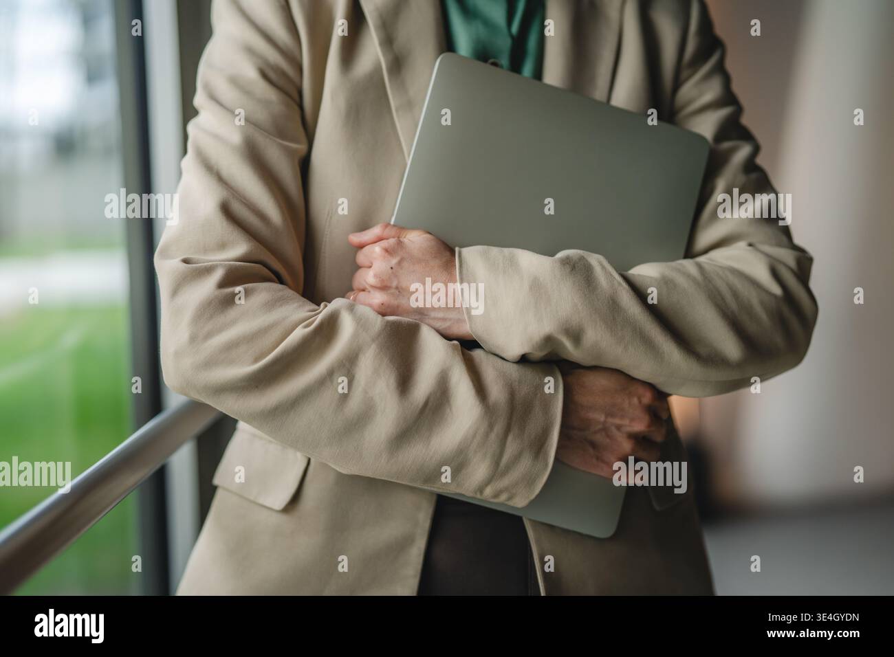 Geschäftsfrau, die ein Unternehmensimage in der Hand hält, während sie ein Notebook hält, symbolisiert Professionalität, Produktivität und moderne Technologie in einer dynamischen Arbeit Stockfoto