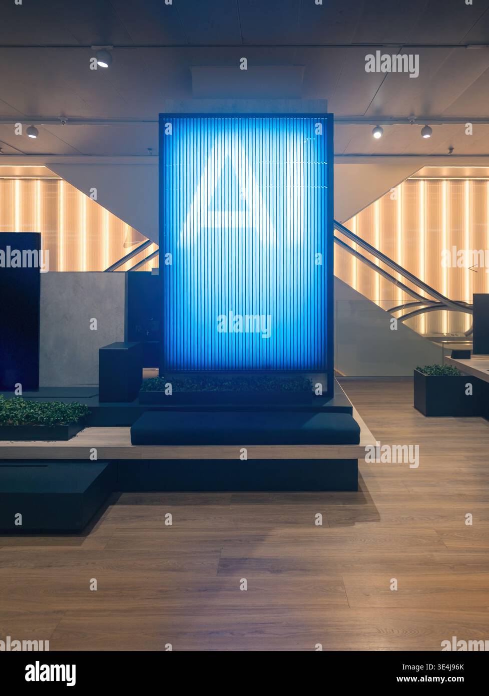 Das moderne Einkaufszentrum verfügt über Holzfußboden und ein beeindruckendes digitales Display. Hellblaue Lichter schaffen ein futuristisches Ambiente, ideal für Re Stockfoto