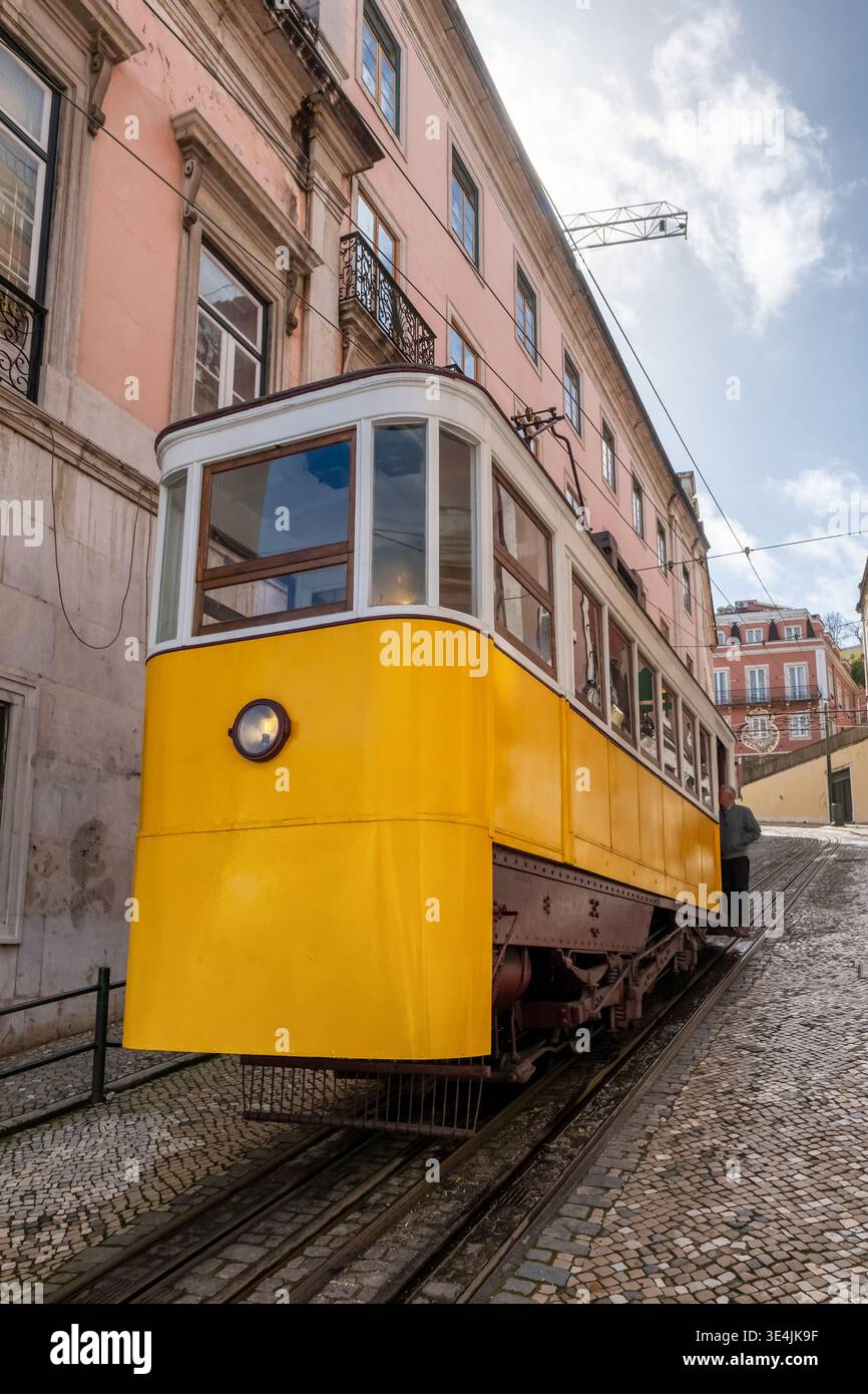 Historische gelbe Standseilbahn Elevador da Gloria an einer steilen Kopfsteinpflasterstraße in Lissabon Stockfoto