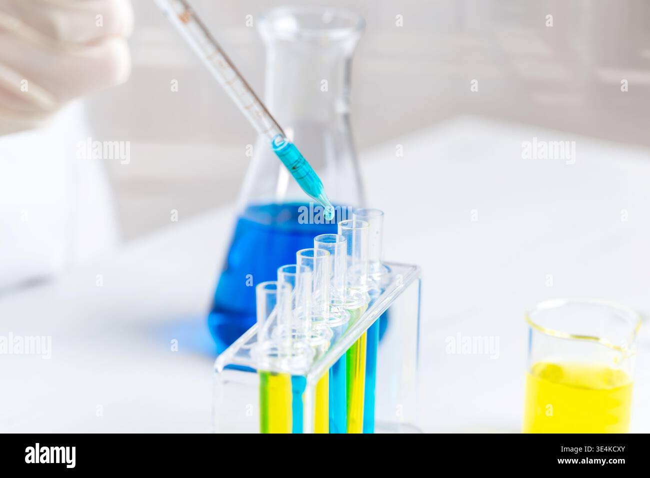 Nahaufnahme der Pipette, die blaue Flüssigkeit in Reagenzgläser, chemische Experimente und Laboranalysen mit farbenfrohen Lösungen abgibt Stockfoto