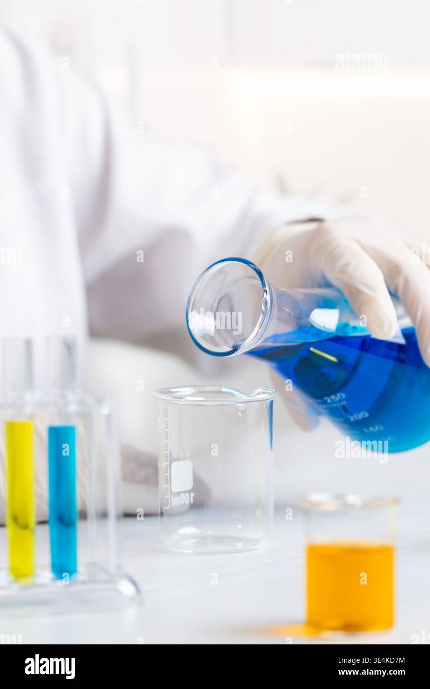Laborgläser mit bunten Flüssigkeiten während chemischer Experimente, wissenschaftlicher Forschung und Analyse mit Schwerpunkt auf dem Mischen von Flüssigkeiten Stockfoto