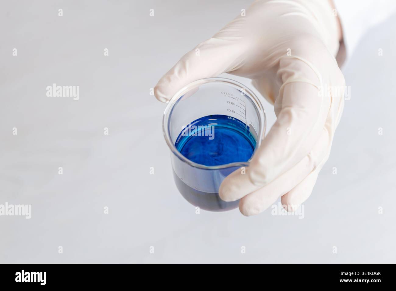 Nahaufnahme des Handbechers mit blauer chemischer Flüssigkeit, Laborversuch und wissenschaftliche Tests Stockfoto