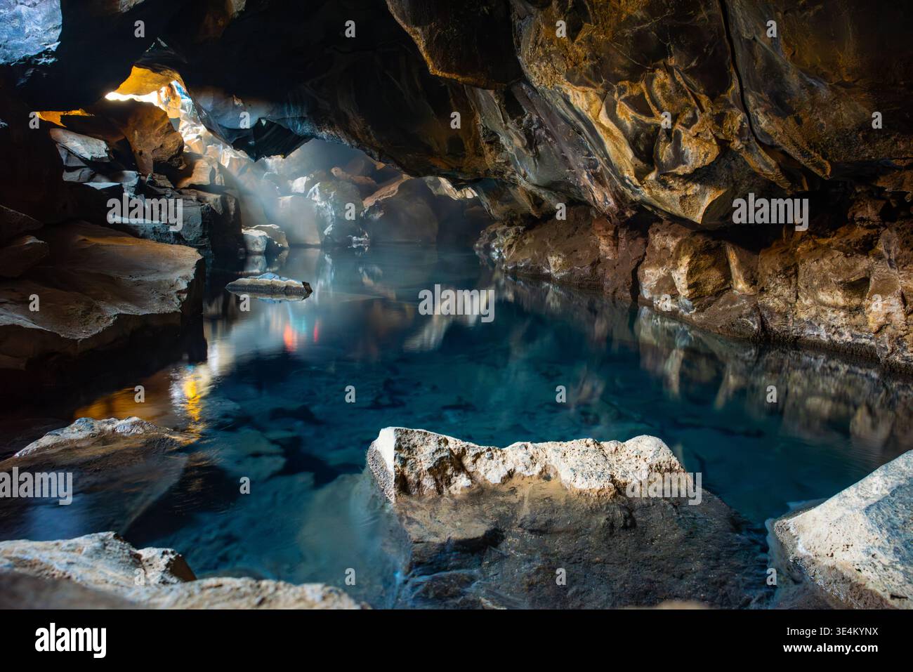 Erleben Sie die einzigartige Landschaft von Myvatn in Island, mit vulkanischen Höhlen mit einem ruhigen blauen Pool. Licht durchfiltert und schafft eine Ruhe Stockfoto