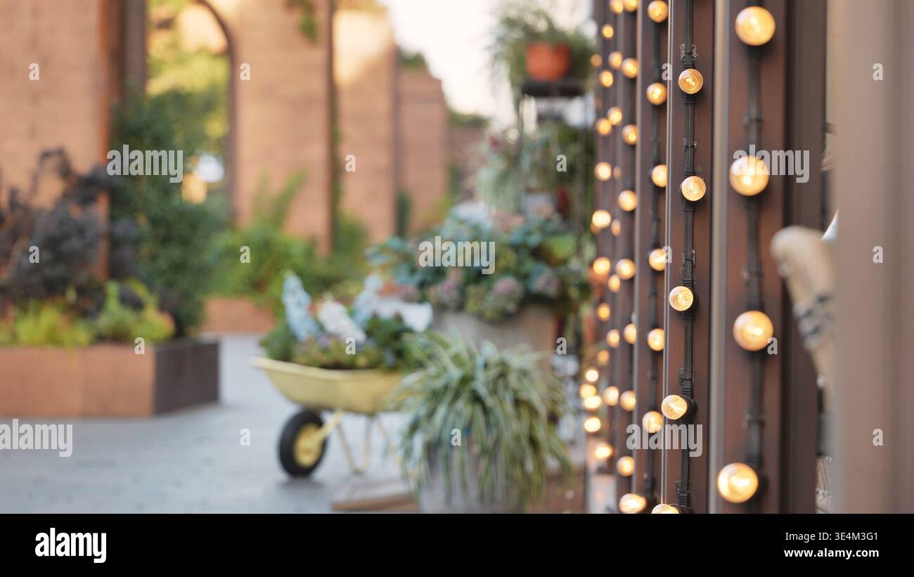 Warme leuchtende Lichterketten in einer rustikalen Gartenterrasse mit weichem Hintergrund Stockfoto