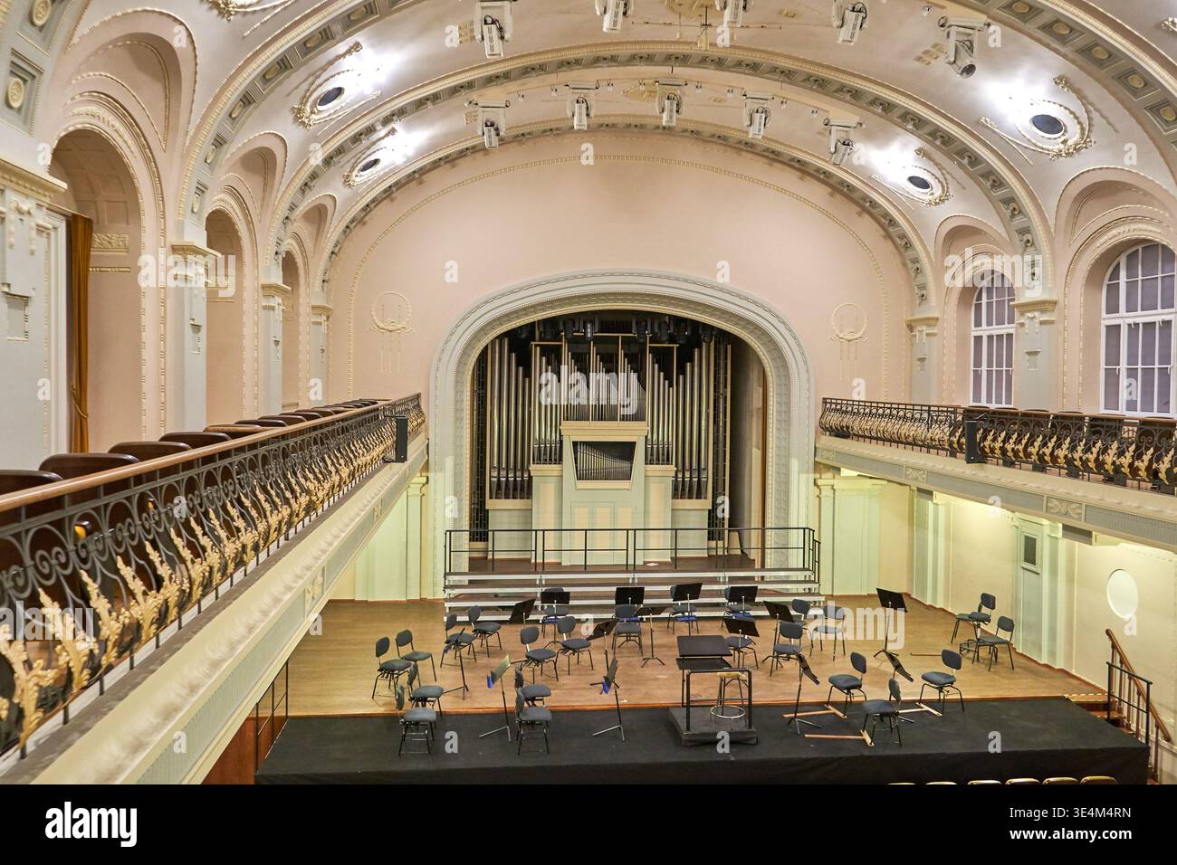 Innenblick auf einen eleganten, leeren Konzertsaal oder Auditorium mit klassischer Architektur und verzierten dekorativen Details. Die Holzbühne ist Stockfoto