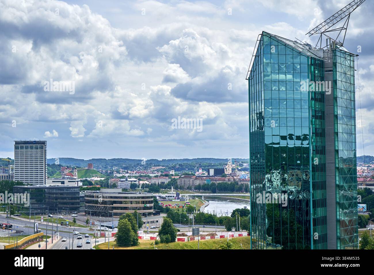 Ein Panoramablick auf die Stadt mit einem modernen Glashochhaus mit reflektierenden, teelinfarbenen Fenstern und einer markanten Metallkrakonstruktion Stockfoto