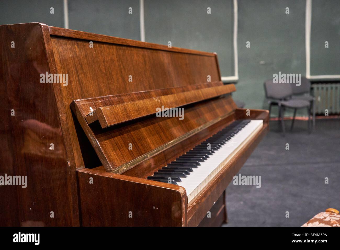 Seitenansicht eines Vintage-Klaviers aus poliertem, dunkelbraunem Holz mit sichtbaren Maserungen. Das Fallboard des Klaviers ist offen und zeigt sich Stockfoto