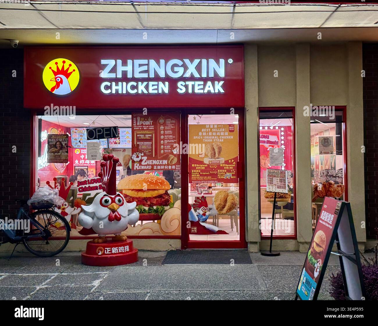Zhengxin Chicken Steak - Burnaby, BC. März 2026. Leuchtende rote Schilder und Hühnermaskottchen heben die moderne asiatische Street Food Szene in der Stadt hervor. Stockfoto