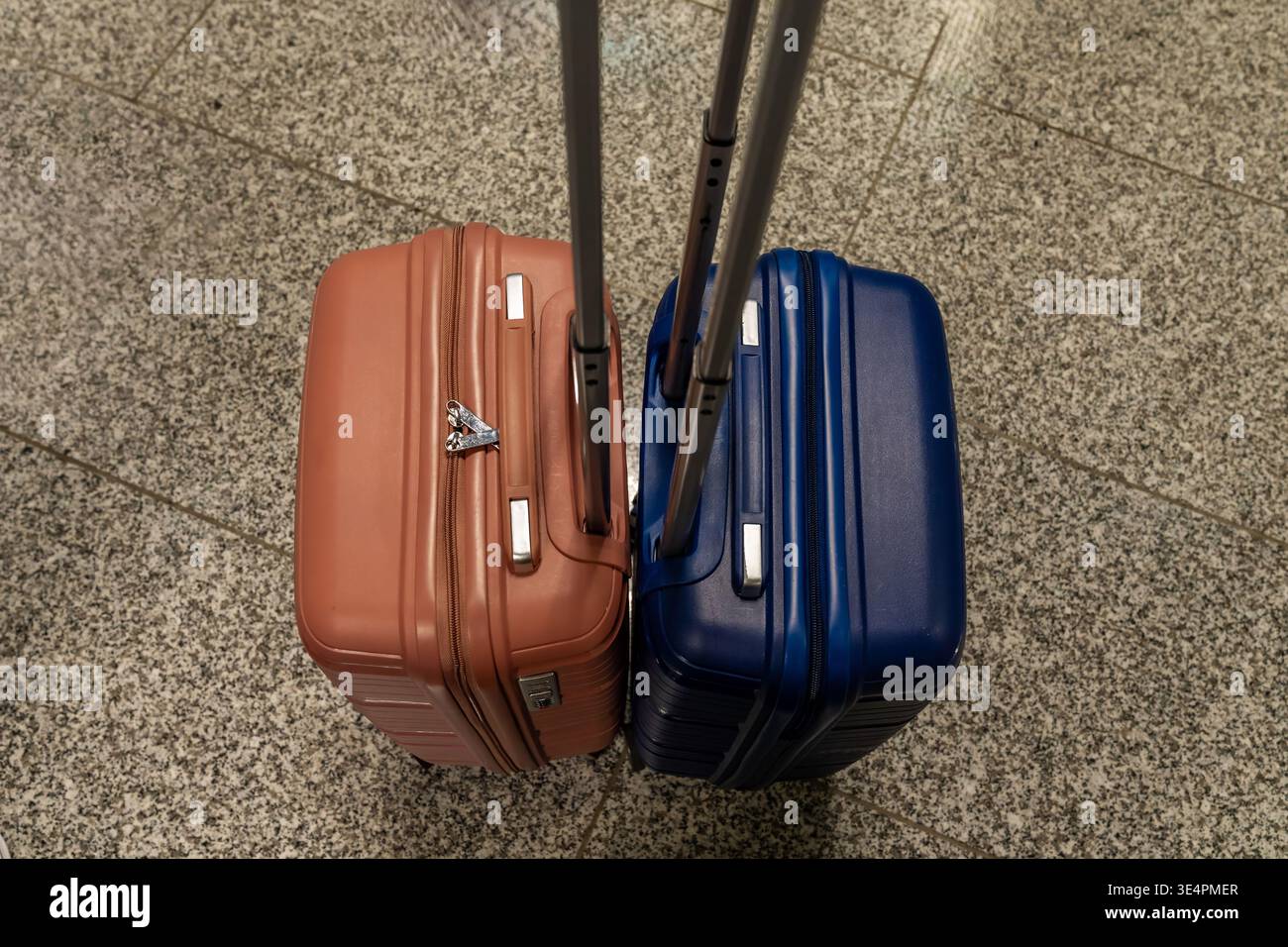 Reisegepäck wartet. Koffer auf der Flughafenetage. Hartschalenreisetaschen stehen neben Granitfliesen. Zwei Koffer mit Rädern liegen auf gesprenkelten Stockfoto