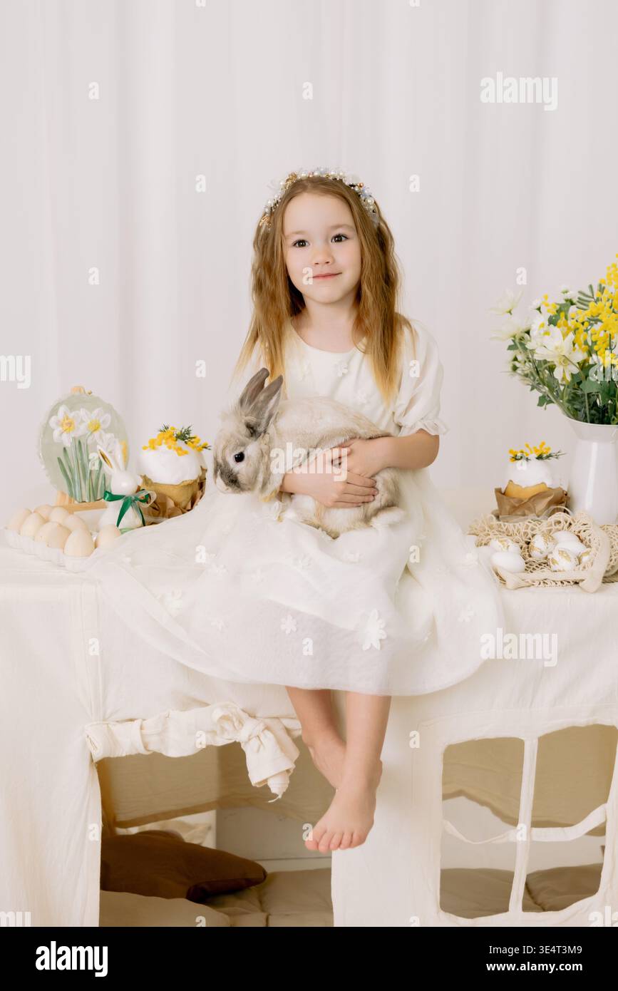Entzückendes Mädchen mit Häschen in weicher Osterdekoration, helles minimales Studioporträt mit Frühlingsstimmung Stockfoto