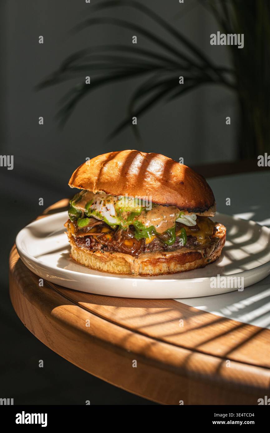 Saftiger Cheeseburger mit Sauce und Gemüse auf Teller Stockfoto