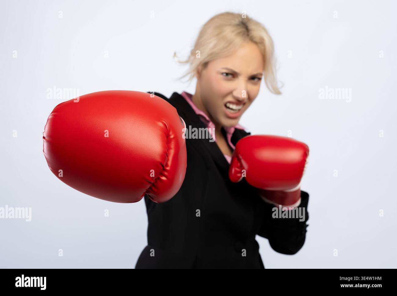 Frau in Business Suit übt Boxen mit roten Handschuhen für Fitness und Ermächtigung Stockfoto