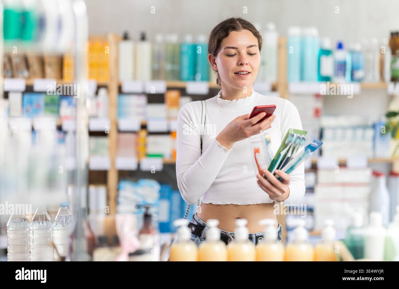 Junge Frau scannt Barcode von Zahnnetzverpackungen in der Apotheke Stockfoto