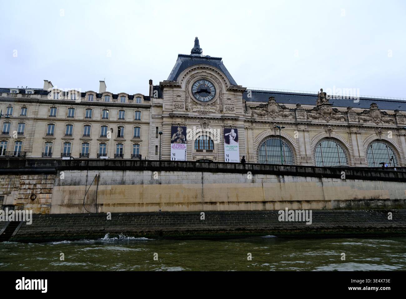 Paris, Frankreich-3. Oktober 2025: Blick auf die Fassade des Musée d'Orsay mit seiner berühmten Uhr und Steindamm entlang der seine Stockfoto