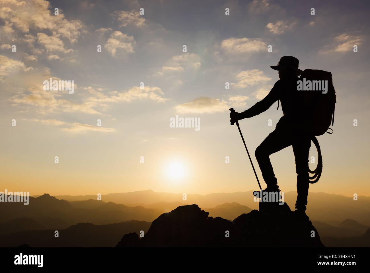 Silhouette eines Kletterers auf der Spitze des felsigen Berges bei Sonnenuntergang, Mann auf der Spitze des Berges. Konzeptdesign. Allein beim Gipfelkletterer erfolgreich Stockfoto