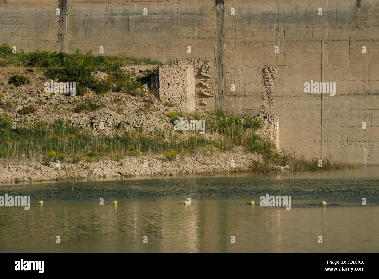 Ein flacher Blick auf die imposante Staumauer des Amadorio Reservoir in Alicante. Spanien. Die massive Betonkonstruktion ragt über einem trockenen. Felsiges Flussbett Stockfoto