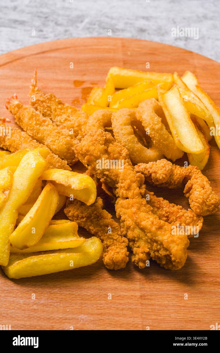 Blick von oben auf gebratene Hähnchennuggets, Garnelen-Zwiebelringe und Pommes frites Stockfoto