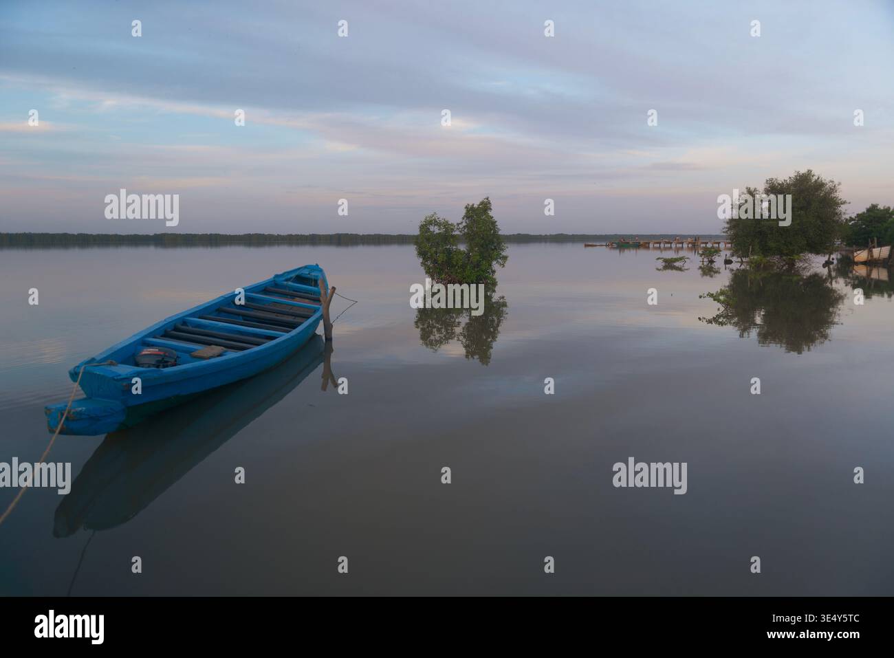 Blick auf ein blaues Holzkanu bei Sonnenuntergang an einem zerbröckelten Steg im Gambia Fluss. Tendaba, Gambia. Stockfoto