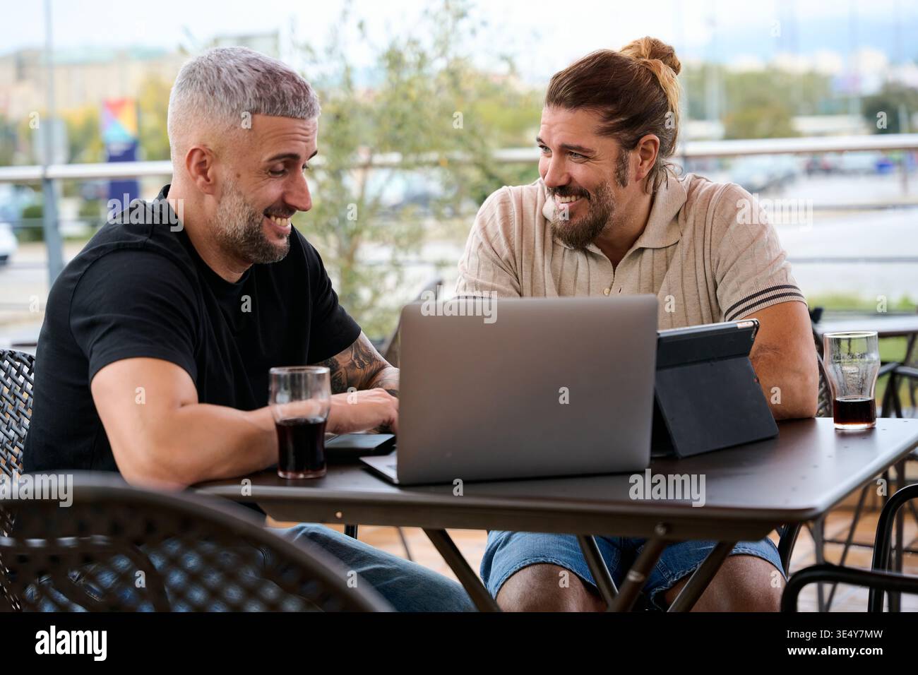 Männliche Freunde genießen Kaffee im Freien und diskutieren gemeinsam über die Arbeit Stockfoto