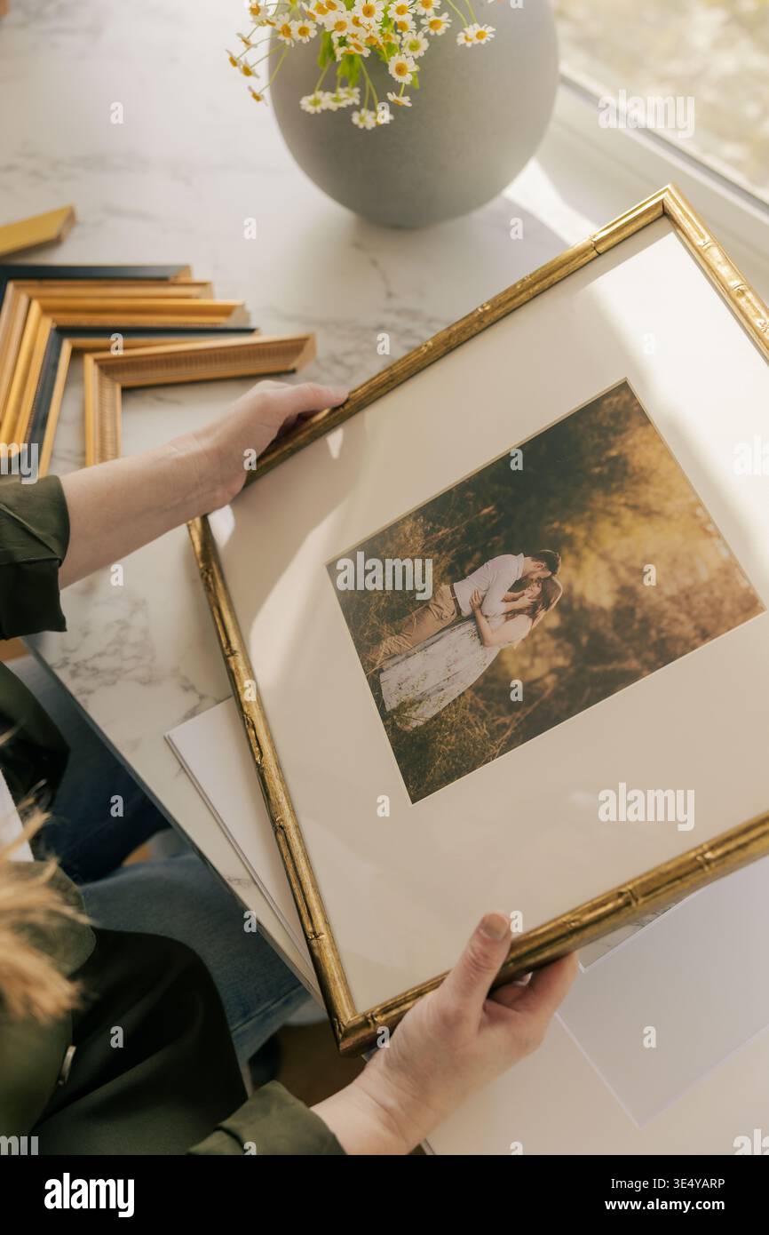 Gerahmter Hochzeitsdruck, der von einer Frau im Haus gehalten wird Stockfoto
