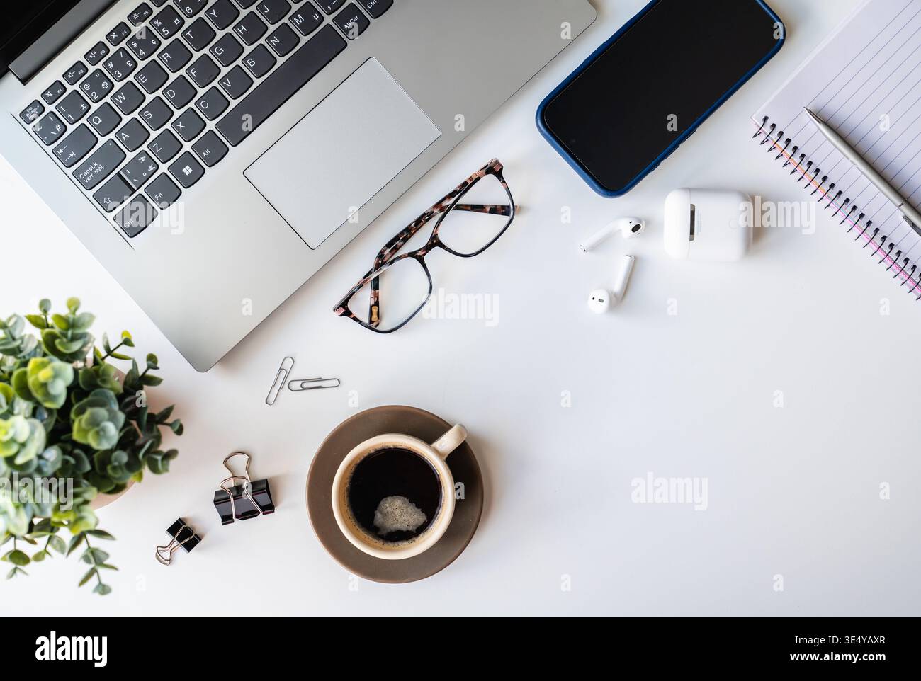 Draufsicht auf weißen Schreibtisch mit Computer, Telefon, Kaffee, Notizblock. Stockfoto