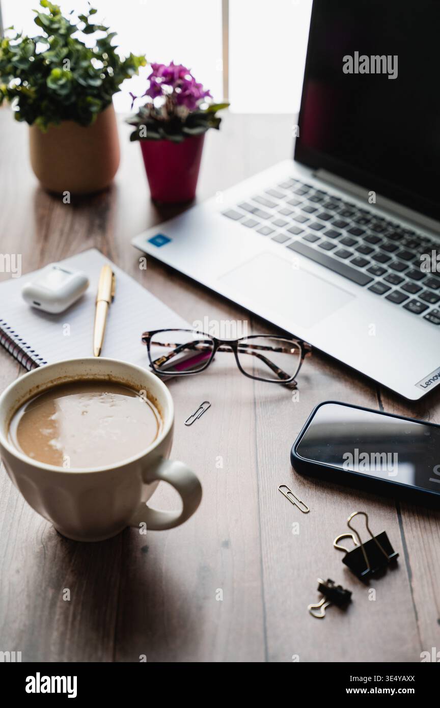 Seitenansicht der Desktop-Arbeitsszene mit Computer, Telefon, Kaffee, Notizblock. Stockfoto