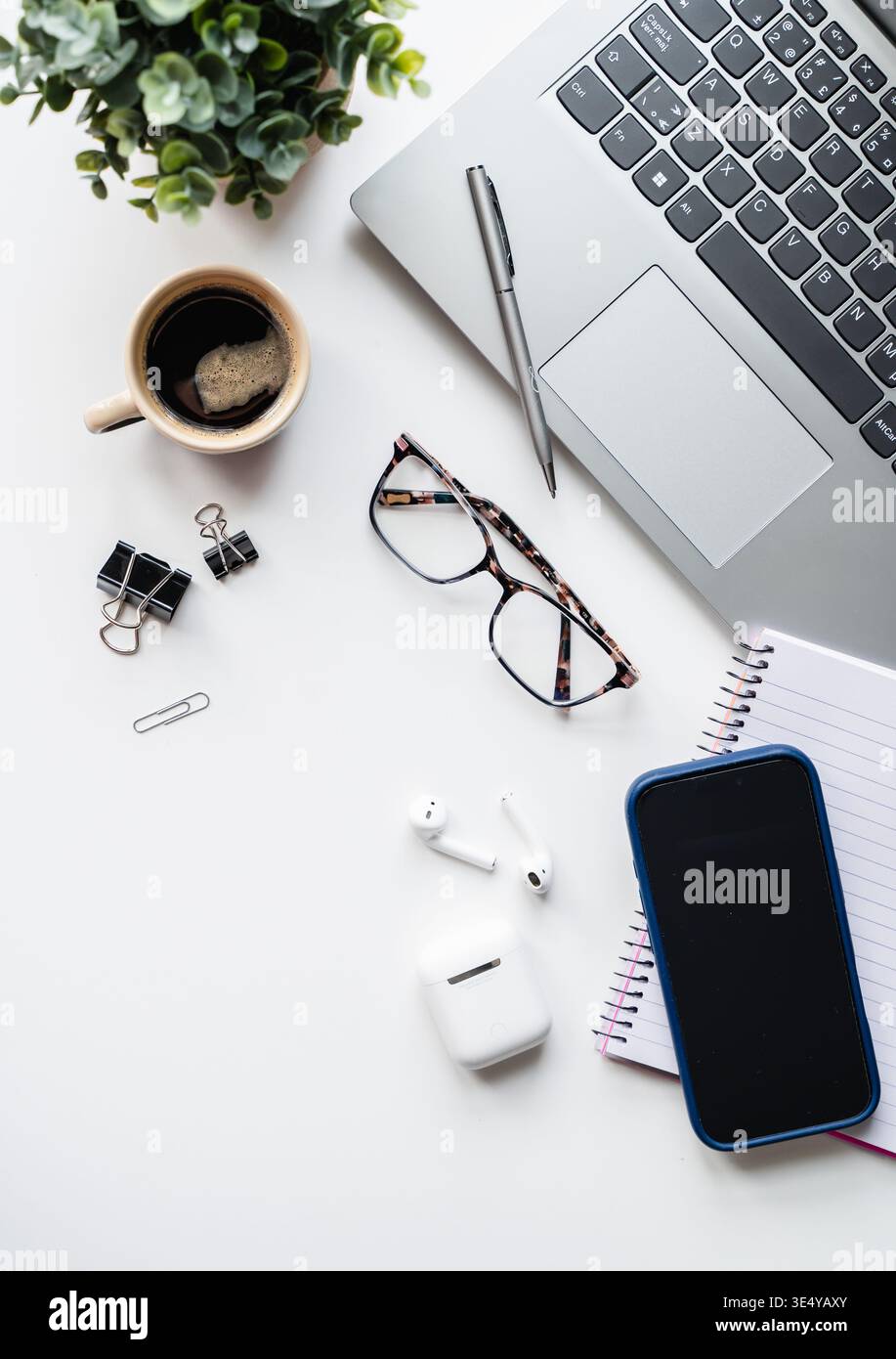 Draufsicht auf weißen Schreibtisch mit Computer, Telefon, Kaffee, Notizblock. Stockfoto