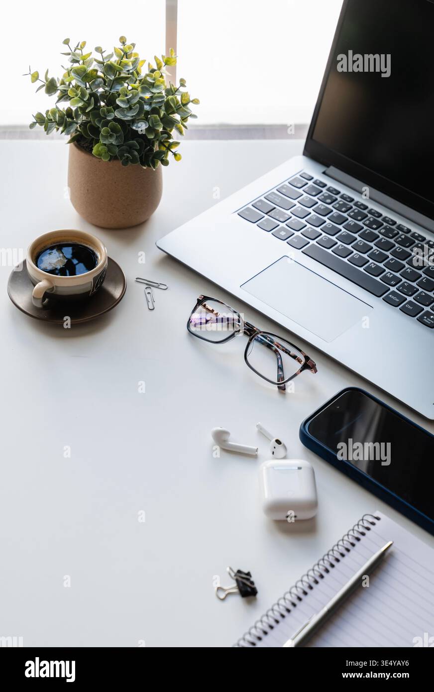 Seitenansicht des weißen Desktops mit Computer, Telefon, Kaffee, Notizblock. Stockfoto