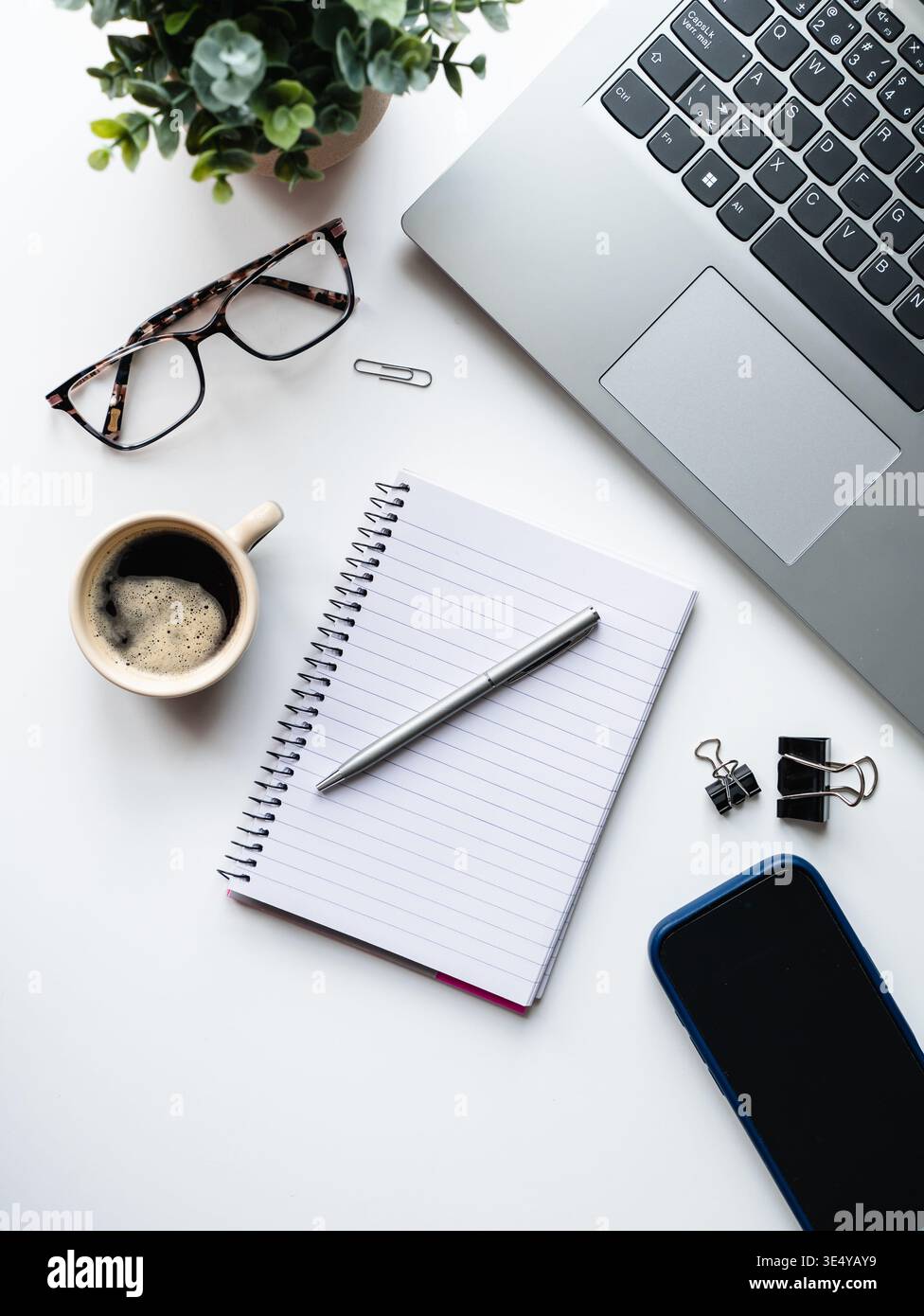 Draufsicht auf die Arbeitsszene mit Computer, Telefon, Kaffee, Notizblock. Stockfoto