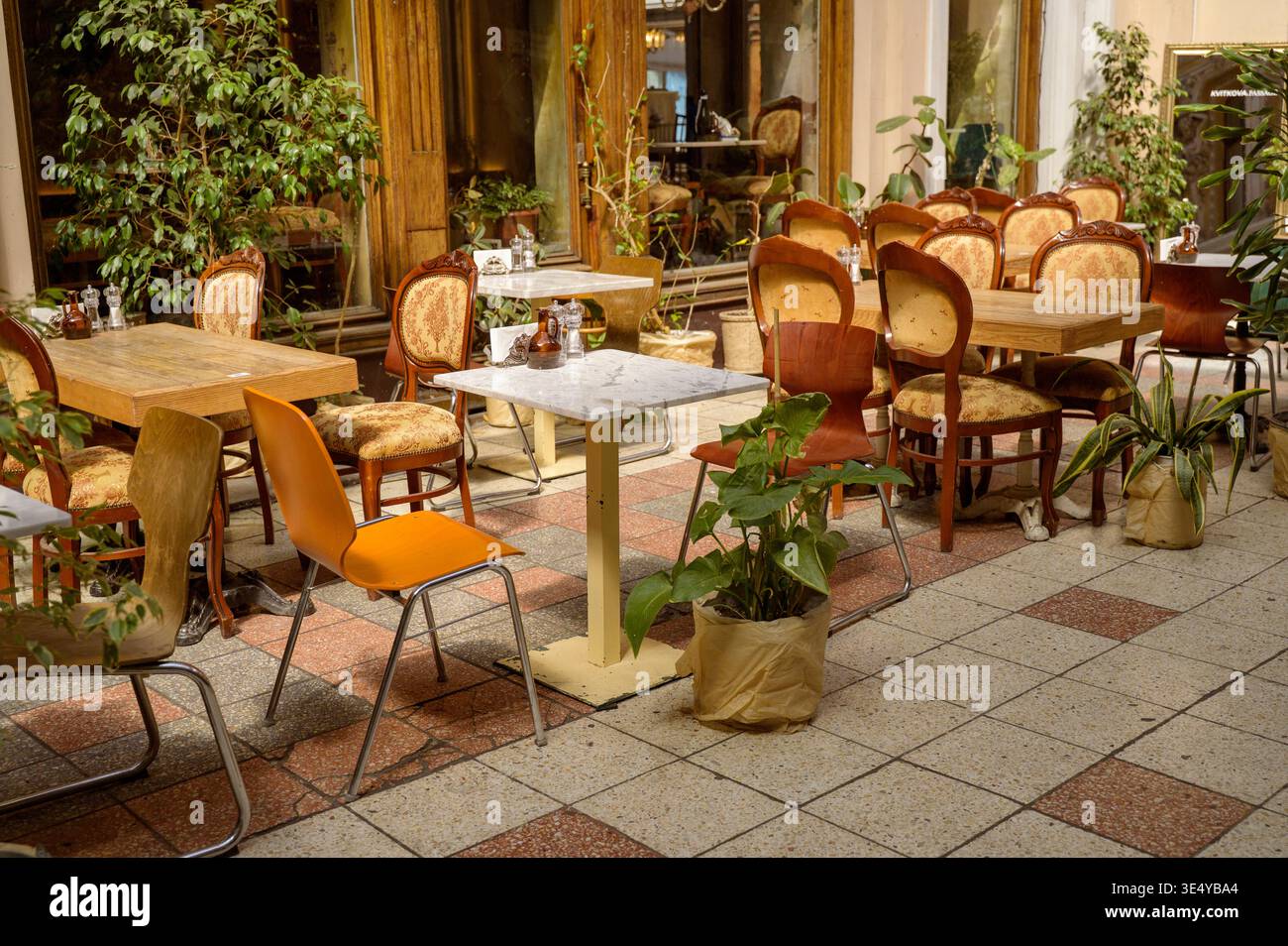 Eine Reihe leerer Tische in einer Sommercafé-Terrasse. Gepflasterter Fußweg in der Nähe. Konzept des saisonalen Tourismushandels und des organisierten Gastgewerbes. Stockfoto