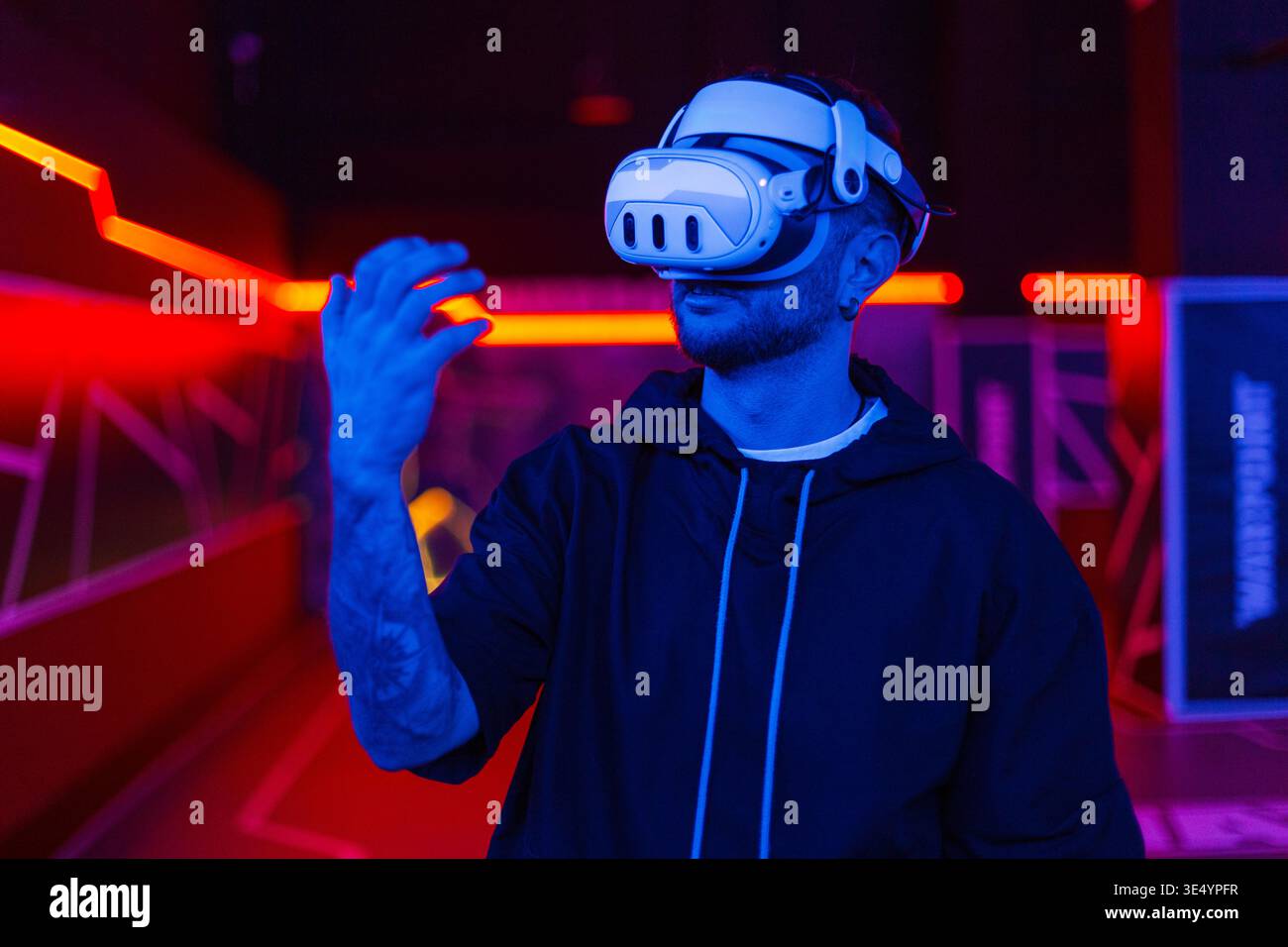 Hübscher cooler junger Mann in einer Brille virtueller Realität auf dunklem Hintergrund mit Neonlicht. VR-Brille. Erweiterte und virtuelle Realität Stockfoto