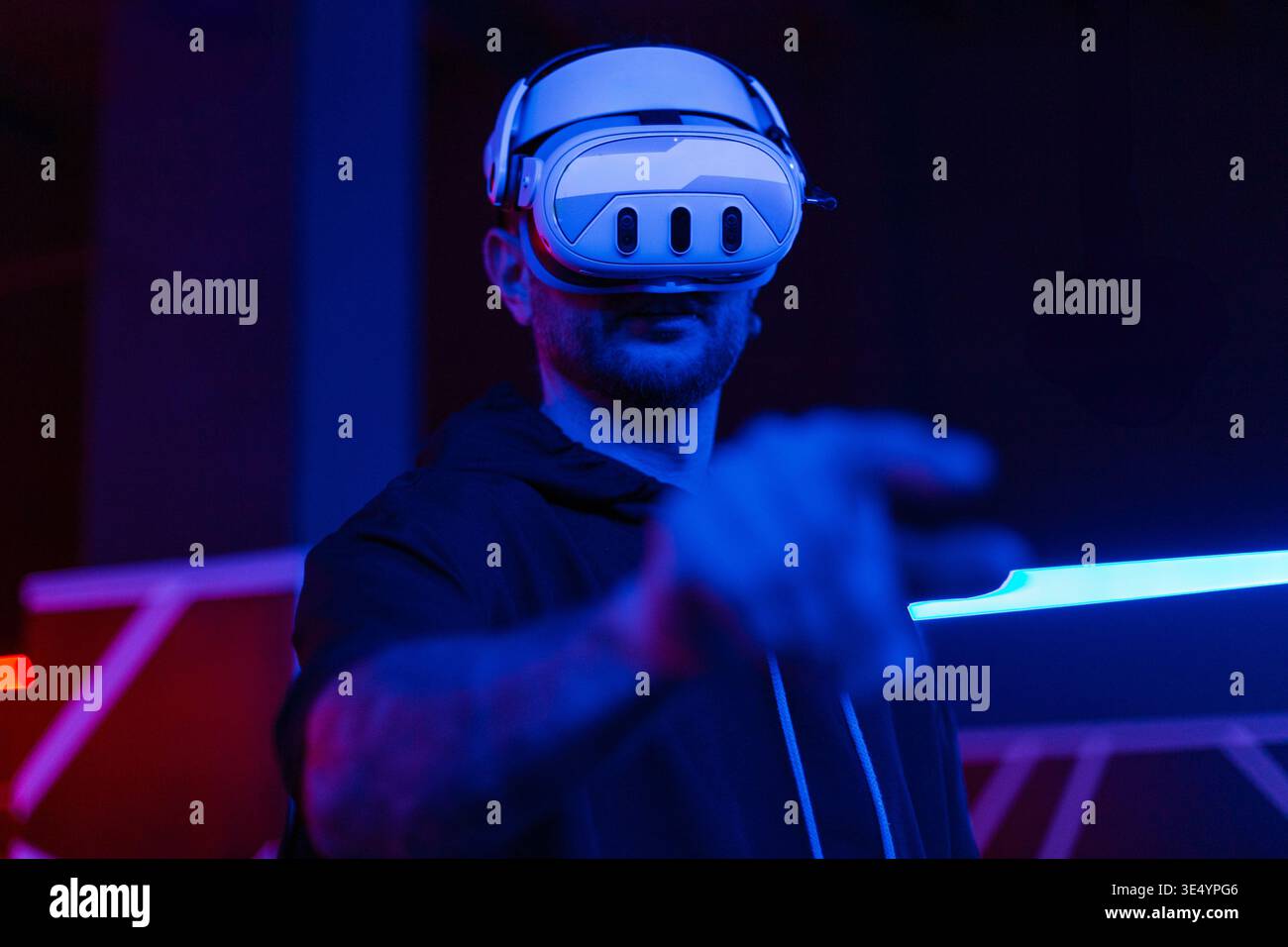 Junger Mann mit Bart in Brille virtueller Realität auf dunklem Hintergrund. Augmented Reality, Wissenschaft, Zukunftstechnologie. VR. Futuristisches 3D-Glas Stockfoto