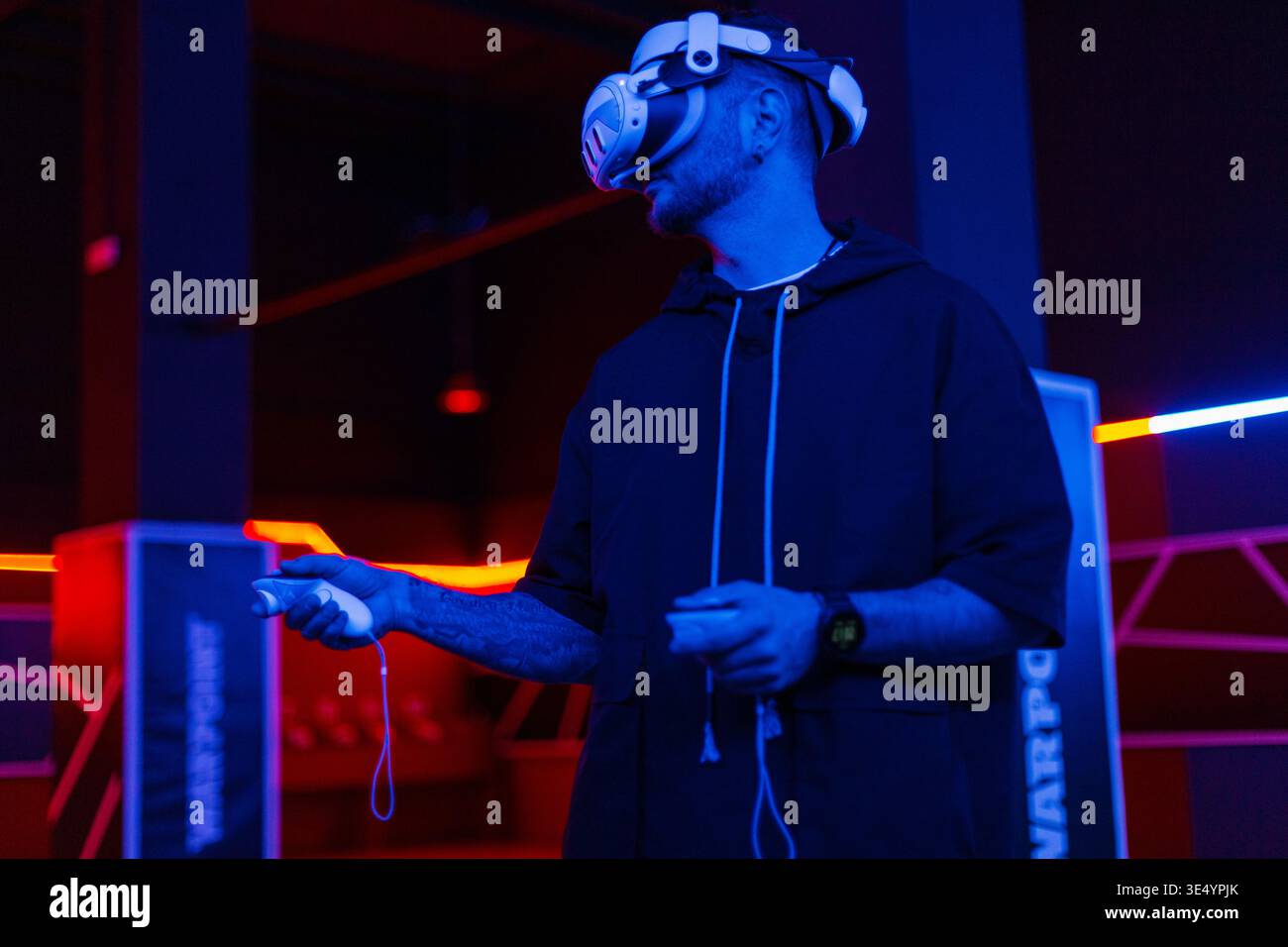 Professioneller Mann-Gamer mit VR-Brille, die Joysticks hält und virtuelles Spiel mit Neonlicht spielt. Technologie und Augmented Reality Stockfoto