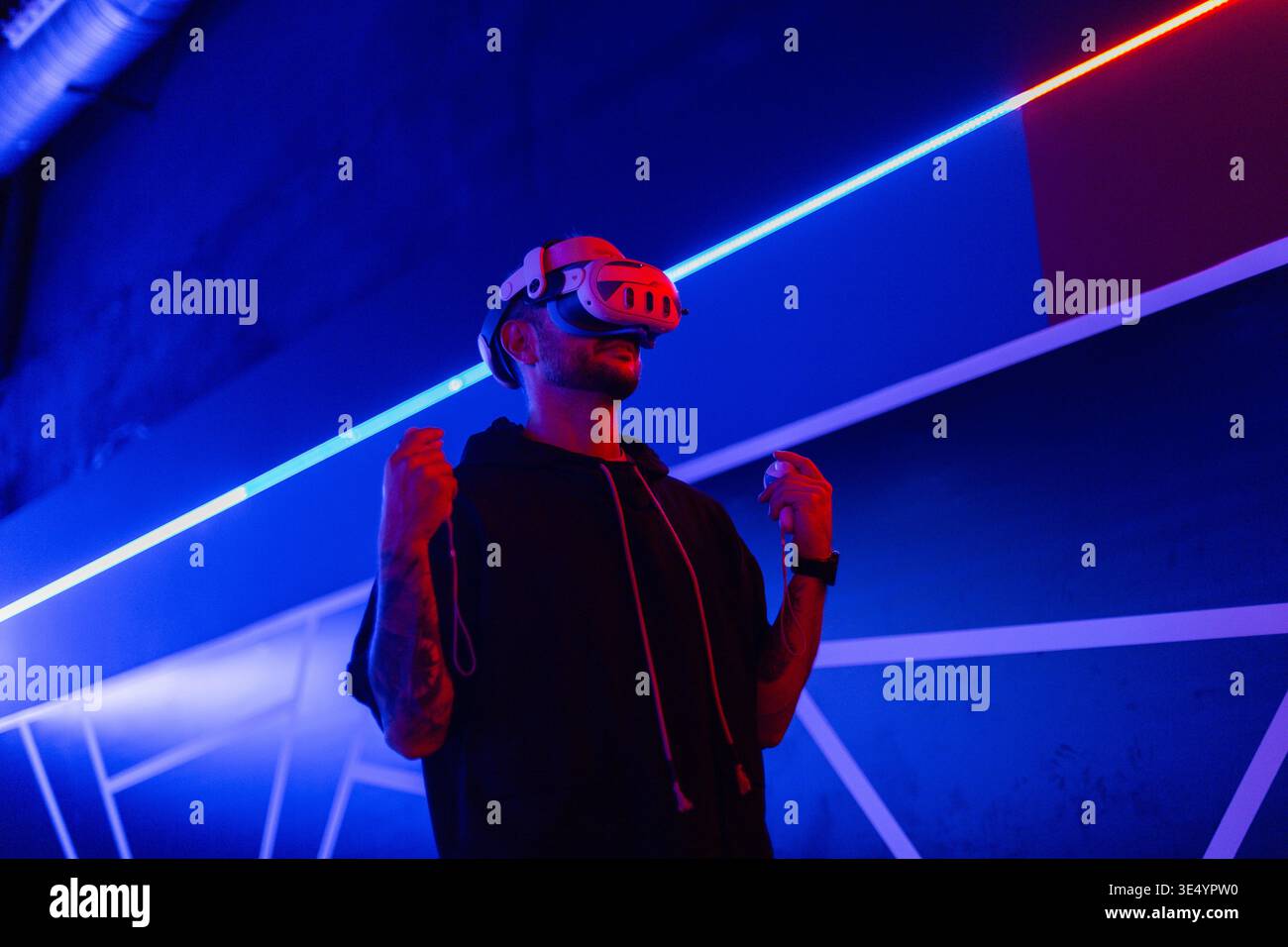 Coole, gutaussehende Mann mit VR-Brille spielt in virtuellen Spielen drinnen mit Neonlicht und rotem Licht. Online-Spiele. Technologie-AR Stockfoto