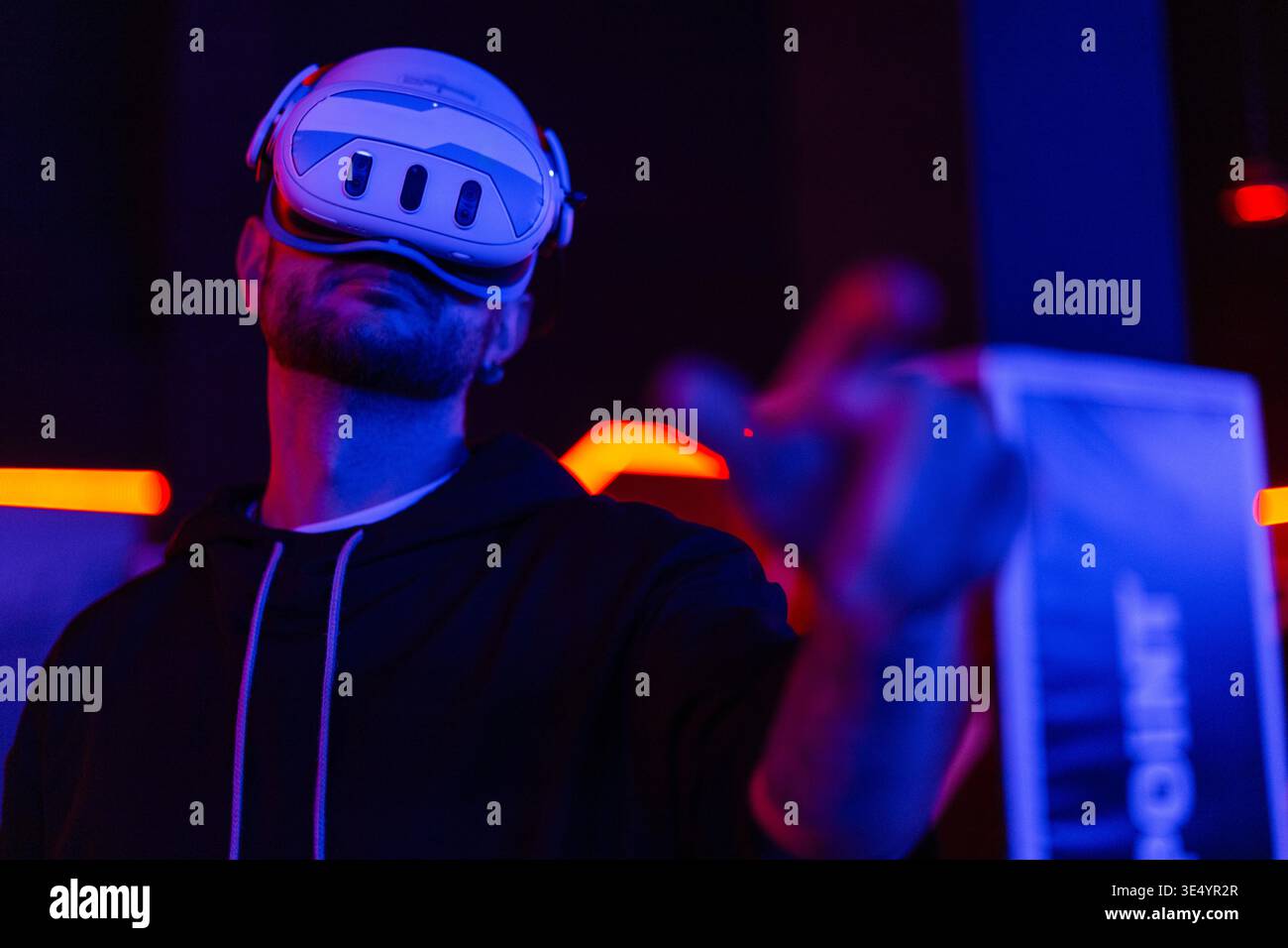 Coole Techniker mit VR-Headset-Brille steuert virtuelles Menü in dunklen Räumen mit Neonlicht Stockfoto